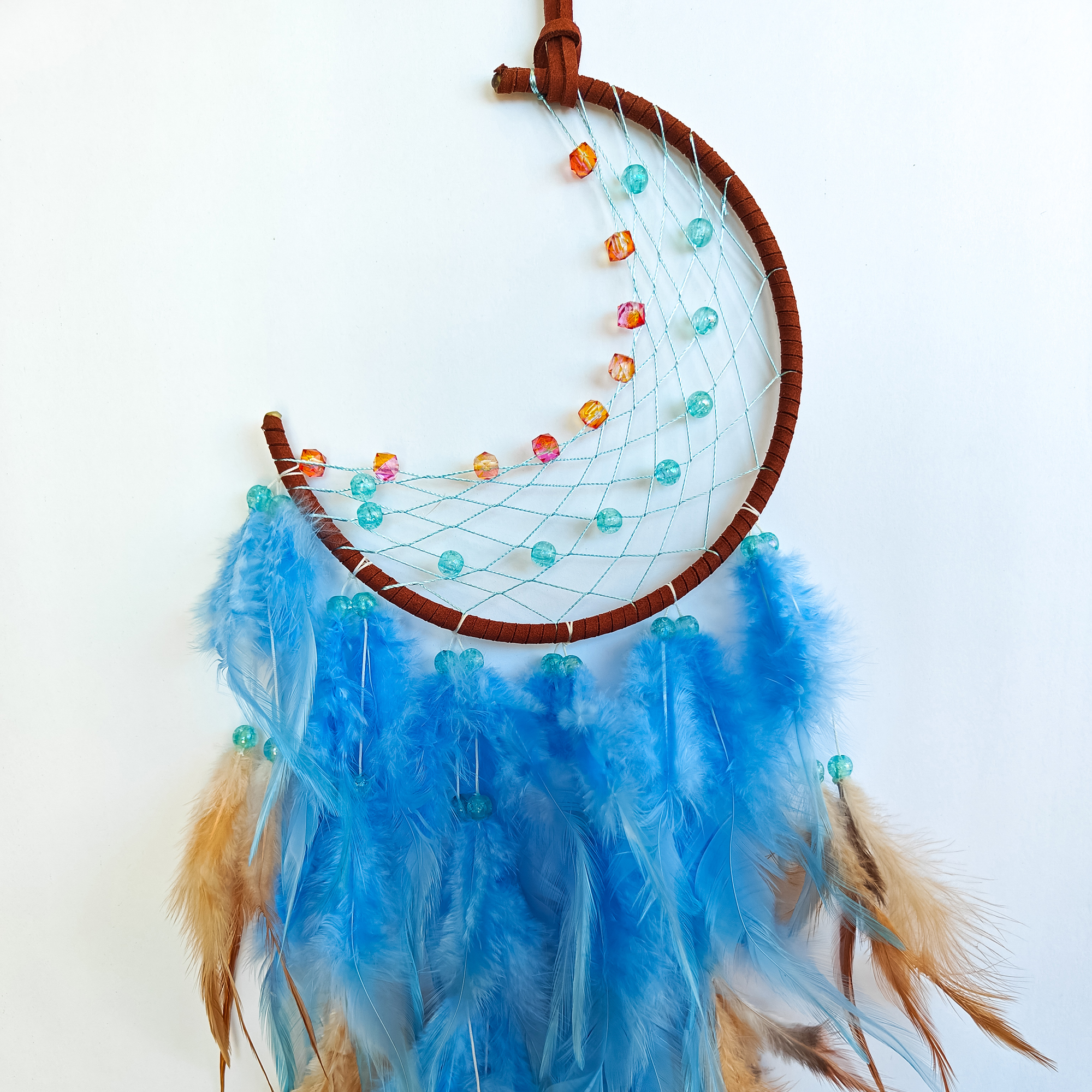 Dreamcatcher with blue feathers and glass beads closeup